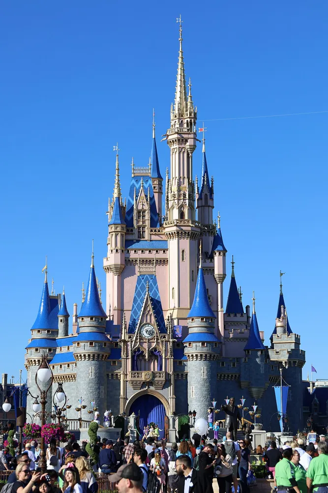 Cinderella Castle with blue rooftops above visitors at Magic Kingdom.