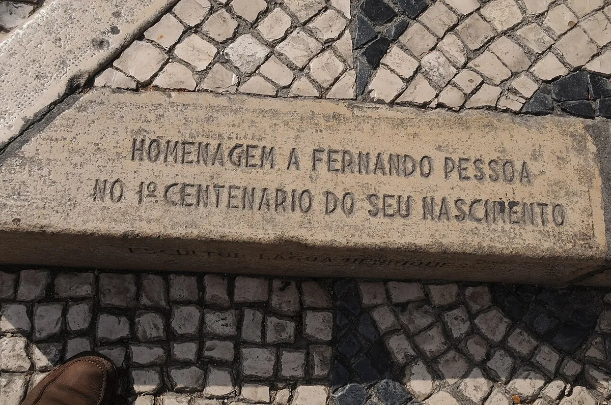 Stone inscription honouring Fernando Pessoa on the centenary of his birth, surrounded by patterned cobblestones.
