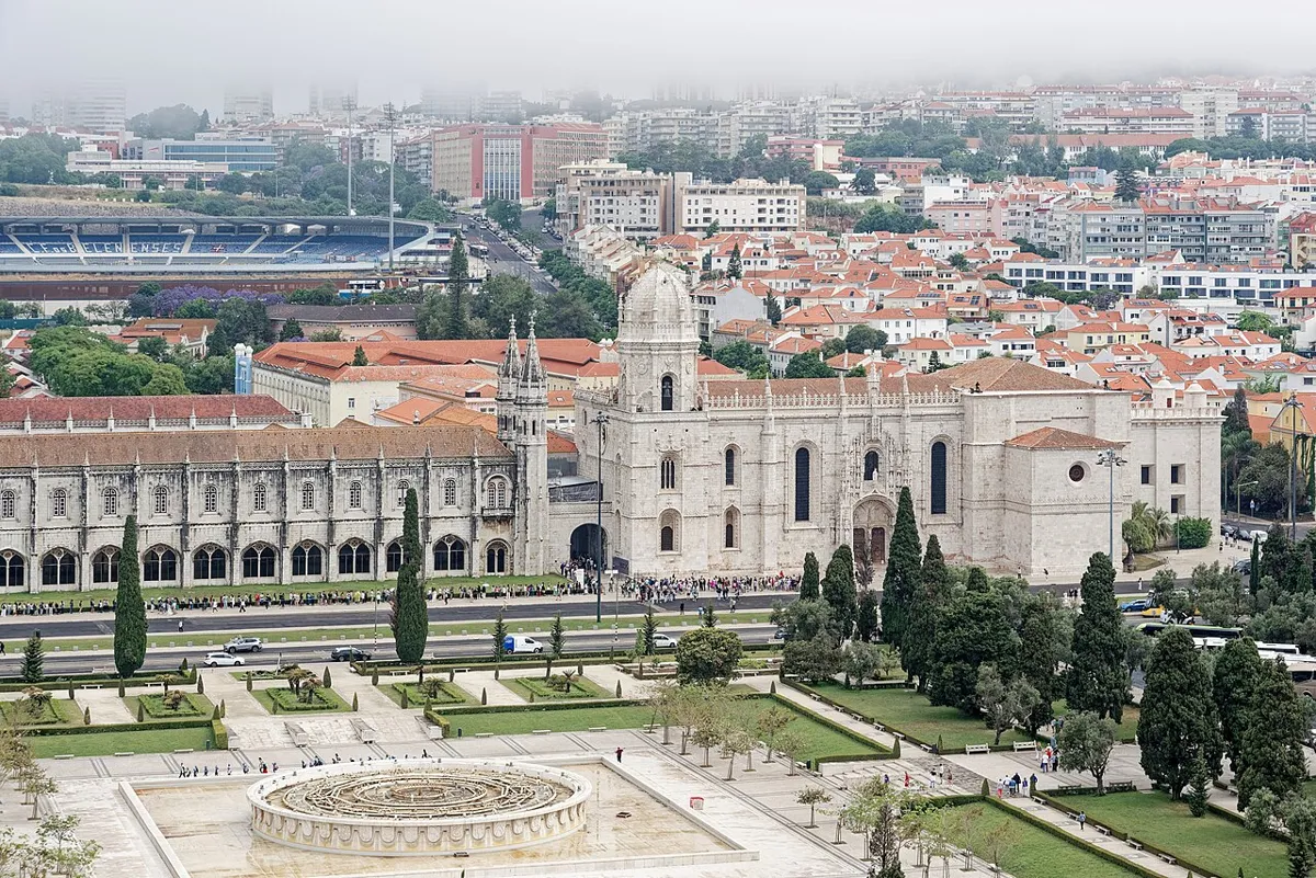 Elevated view of Mosteiro dos Jerónimos, with ornate stone façades, red roofs and formal gardens in the foreground.